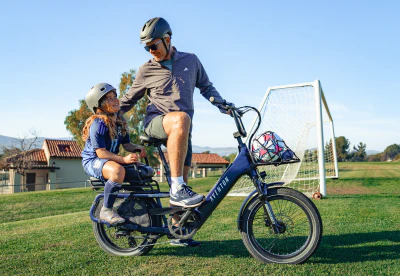 Father carrying his son on an Aventon Sinch.2.5 folding electric bike during a family ride