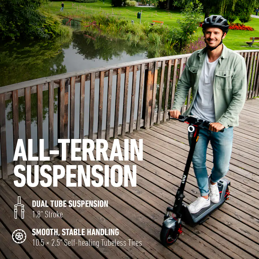 A smiling man riding an electric scooter across a wooden bridge near a scenic park pond.