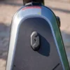 Close-up outdoor shot of the charging port covered by a rubber flap on the front stem enclosure of the NIU KQi300X.