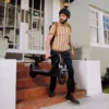 A man wearing a helmet and striped polo shirt carrying a folded electric scooter down house steps.
