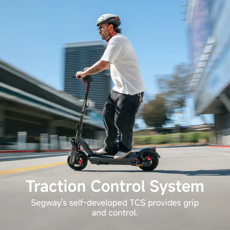 A helmeted man riding a Segway electric scooter down a city street with motion blur in the background, highlighting the traction control system.