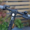 Front-facing view of electric scooter handlebars with an illuminated high-intensity LED headlight and side reflectors.