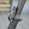 Close-up of the quick-release folding latch mechanism on the steering column of a dark gray electric scooter.